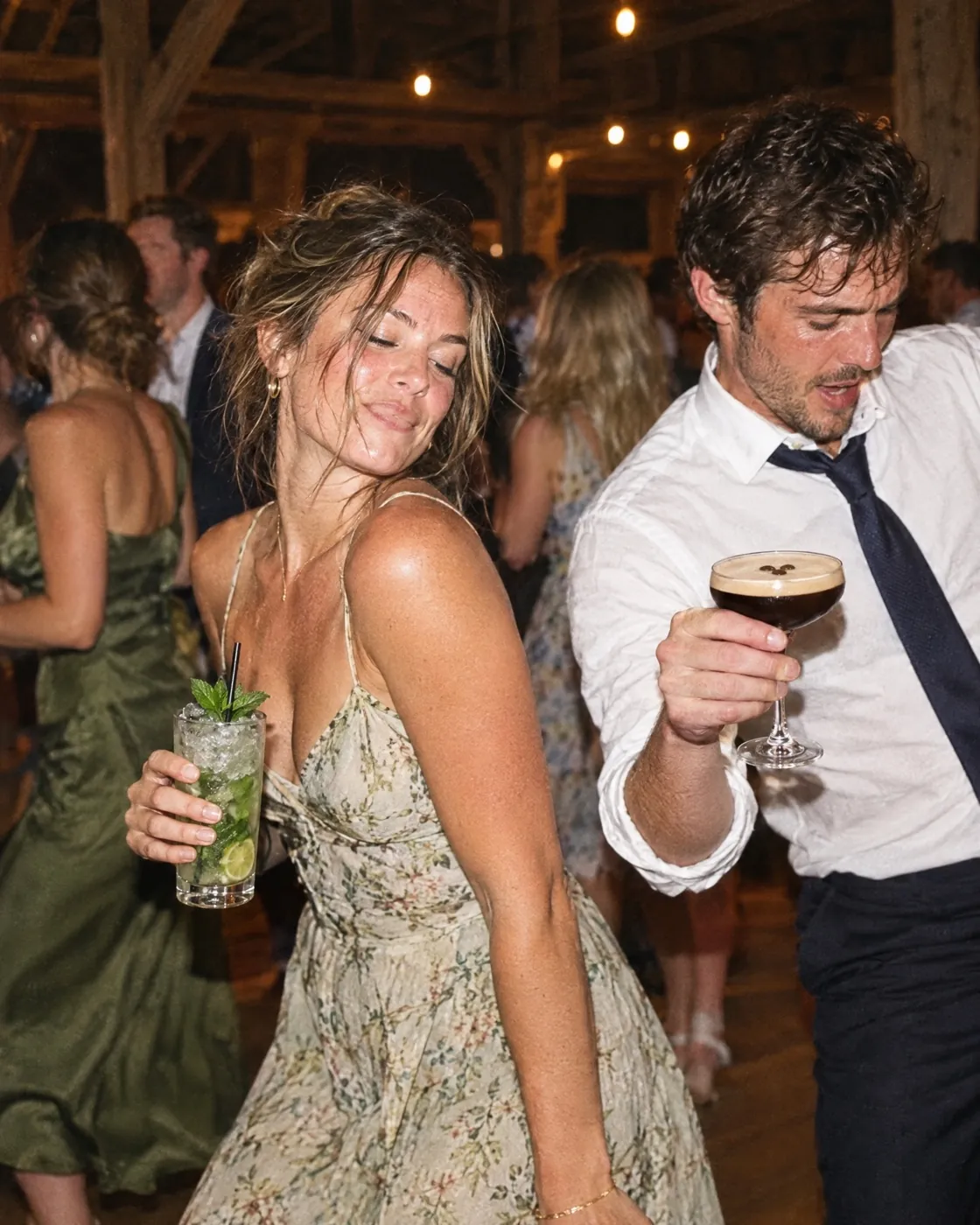 Invités qui dansent dans une grange le soir, un Mojito et un Espresso Martini à la main